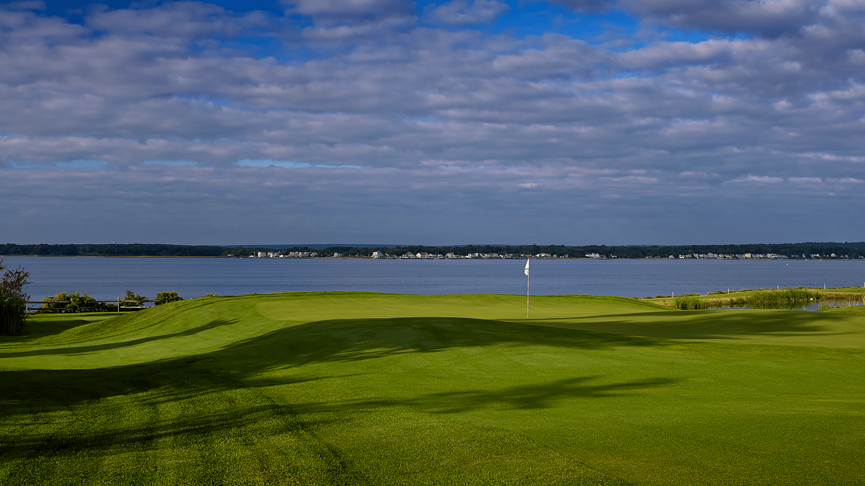 golf green with flag by the water